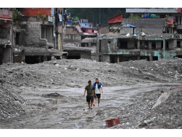 Flash flood survivors walk through sludge past damaged houses searching for salvageable belongings at Trishuli Center in Nepal's Nuwakot district on August 30, 2026. Photo by Arun SANKAR / AFP