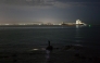 An angler (C) uses a headlamp before casting his line, as a large cargo container ship sails towards the Laem Chabang Port, near the city of Pattaya on September 1, 2026. (Photo by ANTHONY WALLACE / AFP)
