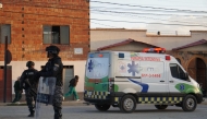 This picture released by APG Noticias shows police officers standing near an ambulance at the site of an explosion at an army barracks in Viacha, Bolivia, on September 4, 2026.  (Photo by APG NOTICIAS / AFP)