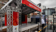 A man wearing a rain jacket stands in front of a booth promoting the 2026 Asian Games in Nagoya, Aichi Prefecture on September 16, 2026. (Photo by Mohd Rasfan / AFP)