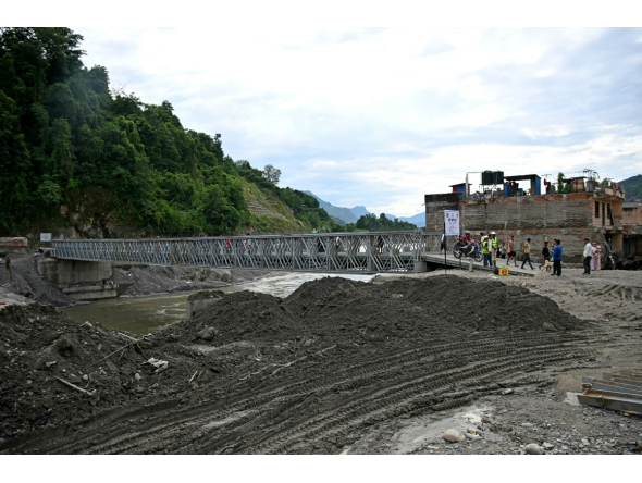 People commute across a bridge over the Tadi river, rebuilt by army personnel in the aftermath of flash floods at Devighat in Nepal's Nuwakot district on September 11, 2026. (Photo by PRAKASH MATHEMA / AFP)
