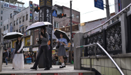 People shield themselves with umbrellas while walking past the metro station entrance in Jongno 3-ga in Seoul on September 20, 2026. (Photo by Lillian SUWANRUMPHA / AFP)