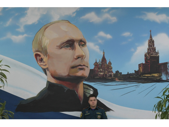 A serviceman of Russia's Emergencies Ministry sits under a mural depicting Russian President Vladimir Putin during Russia's parliamentary election at a polling station in Donetsk, Russian-controlled Ukraine, on September 20, 2026. (Photo by AFP)
