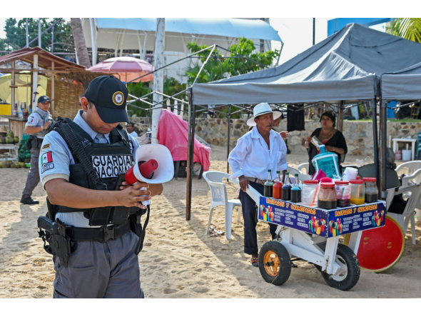 A member of the Mexican National Guard makes an announcement to residents and visitors about the approach of Hurricane Polo along a beach in Acapulco, Guerrero state, Mexico, on September 21, 2026. (Photo by Francisco Robles / AFP)