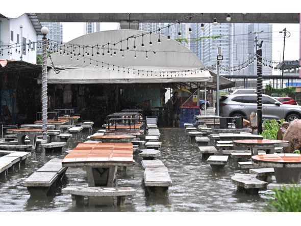 A man looks out from a flooded restaurant in Bangkok on September 26, 2026. (Photo by Lillian Suwanrumpha / AFP)