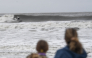 People watch a surfer ride the choppy waves in Ocean City, New Jersey, on September 26, 2026.  (Photo by Matthew HATCHER / AFP)