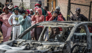 Residents stand behind police tape near the scene where gunmen armed with assault rifles stormed a bar in Johannesburg on September 27, 2026. Photo by EMMANUEL CROSET / AFP