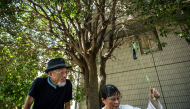 In this picture taken on August 25, 2026, activists Kaoru Morimoto (L) and Susumu Nirasawa check the temperature under a tree in the Nakano district of Tokyo. (Photo by Philip Fong / AFP)
