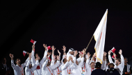 Members of the Qatar delegation celebrate as high jump legend Mutaz Barshim carries the OCA flag during the closing ceremony. (Xinhua)
