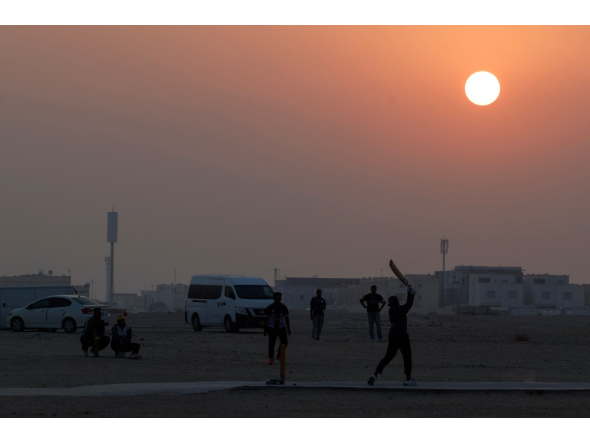 Foreign workers play cricket at sunset in Doha on October 1, 2026. (Photo by KARIM JAAFAR / AFP)
