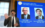 The chair of the Nobel Committee for Chemistry Heiner Linke (L) explains the field of research of Nobel Prize winners France's Henri Kagan and Japan's Kenso Soai (displayed on the screen in background) during a press conference in Stockholm, Sweden, on October 7, 2026. (Photo by Jonathan Nackstrand / AFP)