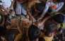 This photo taken on October 6, 2026, shows the children of Nihaya Al-Masri, sharing a meal provided by a charity kitchen in Khan Yunis, in the southern Gaza Strip. (Photo by Bashar Taleb / AFP)