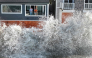 In an aerial view, people watch from a home as a Pacific Ocean wave crashes into a seawall protecting homes amid powerful surf on October 9, 2026 in Long Beach, California. (Photo by Mario Tama/Getty Images/AFP ) 
