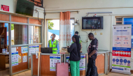 Travellers receive information from health officials near Ebola awareness posters before crossing the border at the Busia One Stop Border Post (OSBP) on the Kenya-Uganda border as health authorities step up Ebola screening measures, in Busia on October 12, 2026. (Photo by Bright Emoja / AFP)
