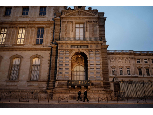 (Files) Police officers walk next to posts newly installed on the sidewalk along the Louvre Museum, on Quai Francois Mitterrand, in Paris on December 12, 2025. (Photo by Anna Kurth / AFP)