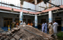 People gather around debris and rubble lying in the courtyard of a school following a roof collapse, in Peshawar on October 15, 2026. Photo by Abdul MAJEED / AFP