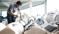 A technician inspects oxygen concentrators awaiting repair and cleaning at a medical supply warehouse in Kuala Lumpur on October 15, 2026. (Photo by Mohd Rasfan / AFP) 