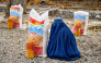 An Afghan burqa-clad woman sits next to food aid distributed by a local charity foundation in Mazar-i-Sharif. (AFP)