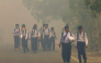 Schoolchildren walk along a smoke-shrouded road in Tegal Arum, Banjarbaru, South Kalimantan, on October 20, 2026, as massive forest and land fires blanket the area in thick haze. (Photo by Muda Sagala / AFP)