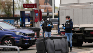 Police officers look at evidences on a site of a petrol station where a man opened fire from his car, killing one person and injuring four others according to police sources, in Trappes, Paris' suburb on October 23, 2026. Photo by Dimitar DILKOFF / AFP