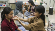 A volunteer (R) assists a woman with a nasal oxygen cannula at a shelter to aid residents experiencing respiratory difficulties in Palangkaraya, Central Kalimantan province on October 26, 2026. Photo by REINA / AFP