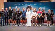 QMMF President Abdulrahman Al-Mannai and QMMF Executive Director Amro Al-Hamad pose for a photo with drivers and riders.
