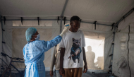 A health worker takes the temperature of a traveller after arriving in Bimbo district south-west of Bangui, on October 28, 2026. (Photo by AFP)