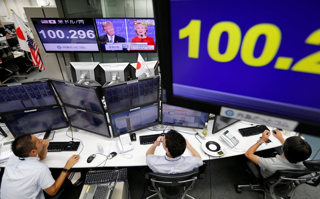 Employees of a foreign exchange trading company work near monitors displaying first US presidential debate between US Republican nominee Donald Trump and Democratic presidential nominee Hillary Clinton (top C), and the Japanese yen's exchange rate against