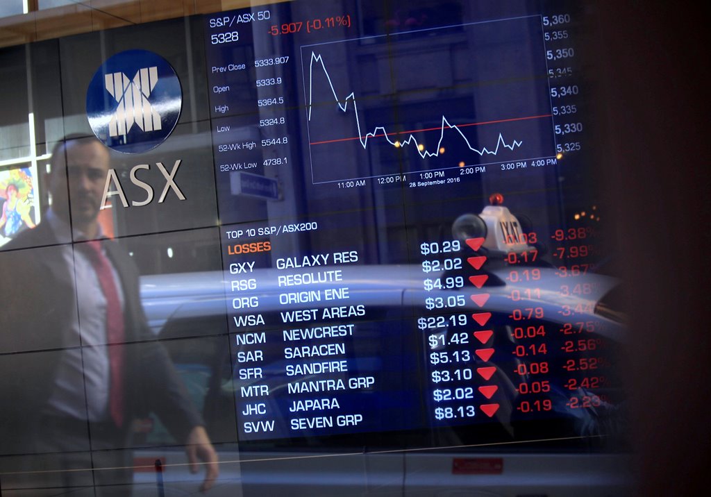 A pedestrian is reflected in a window with a board displaying stock prices at the Australian Securities Exchange (ASX) in Sydney, Australia, September 28, 2016. Reuters/Steven Saphore