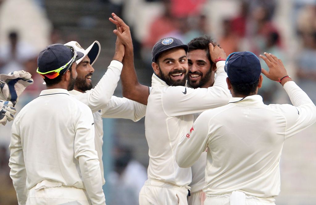 India's Bhuvneshwar Kumar (R) with teammates including captain Virat Kohli celebrate after the wicket of New Zealand's Matt Henry during the second day of the second Test match between India and New Zealand at The Eden Gardens Cricket Stadium in Kolkata o