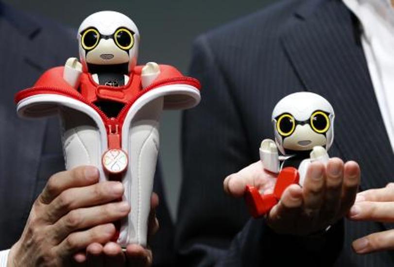 In this Sept. 27, 2016 photo, Toyota Motor Corp. SMO Moritaka Yoshida, right, and Fuminori Kataoka, project general manager from Toyota Motor Corp., pose for photographers with compact sized humanoid communication robots, Kirobo Mini.(AP Photo/Shizuo Kam)