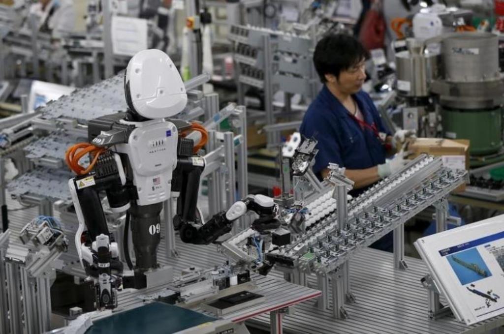 A humanoid robot works side by side with employees in the assembly line at a factory of Glory Ltd., a manufacturer of automatic change dispensers, in Kazo, north of Tokyo, Japan. REUTERS/Issei Kato