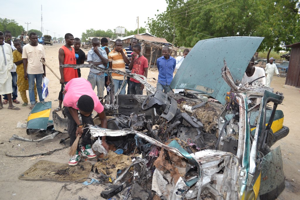 People gather at the site of a car blast in Maiduguri, northeast Borno State in Nigeria, on October 12, 2016 where 8 people were killed and dozen injured. / AFP / STRINGER.