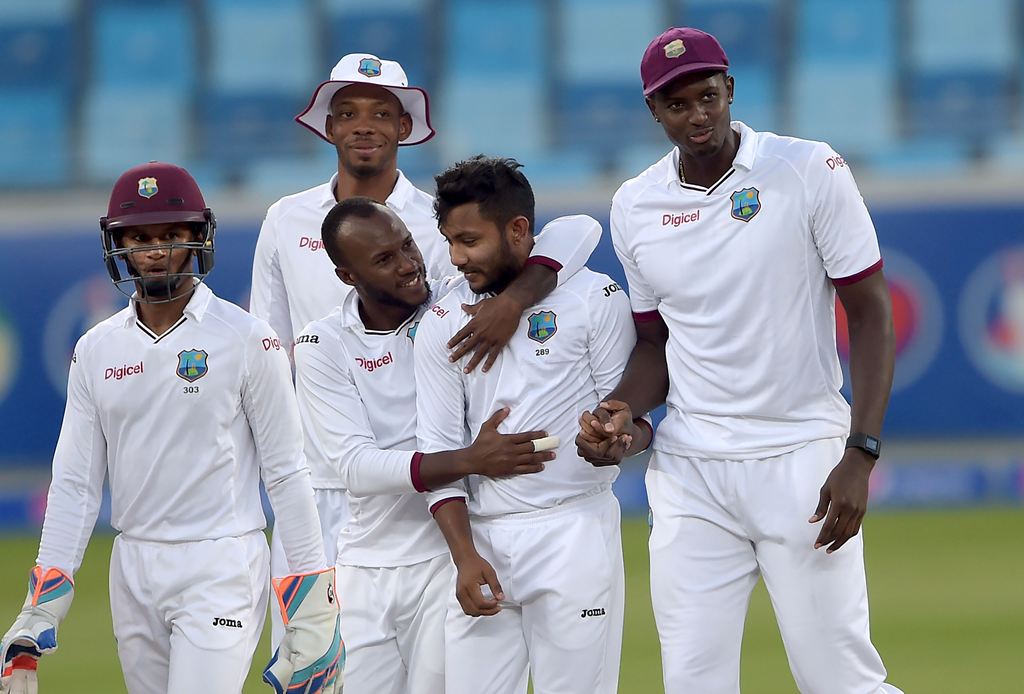 West Indies spinner Devendra Bishoo (2R) celebrates with his teammates after taking the wicket of Pakistani batsman Asad Shafiq on the fourth day of the first day-night Test between Pakistan and the West Indies at the Dubai International Cricket Stadium i