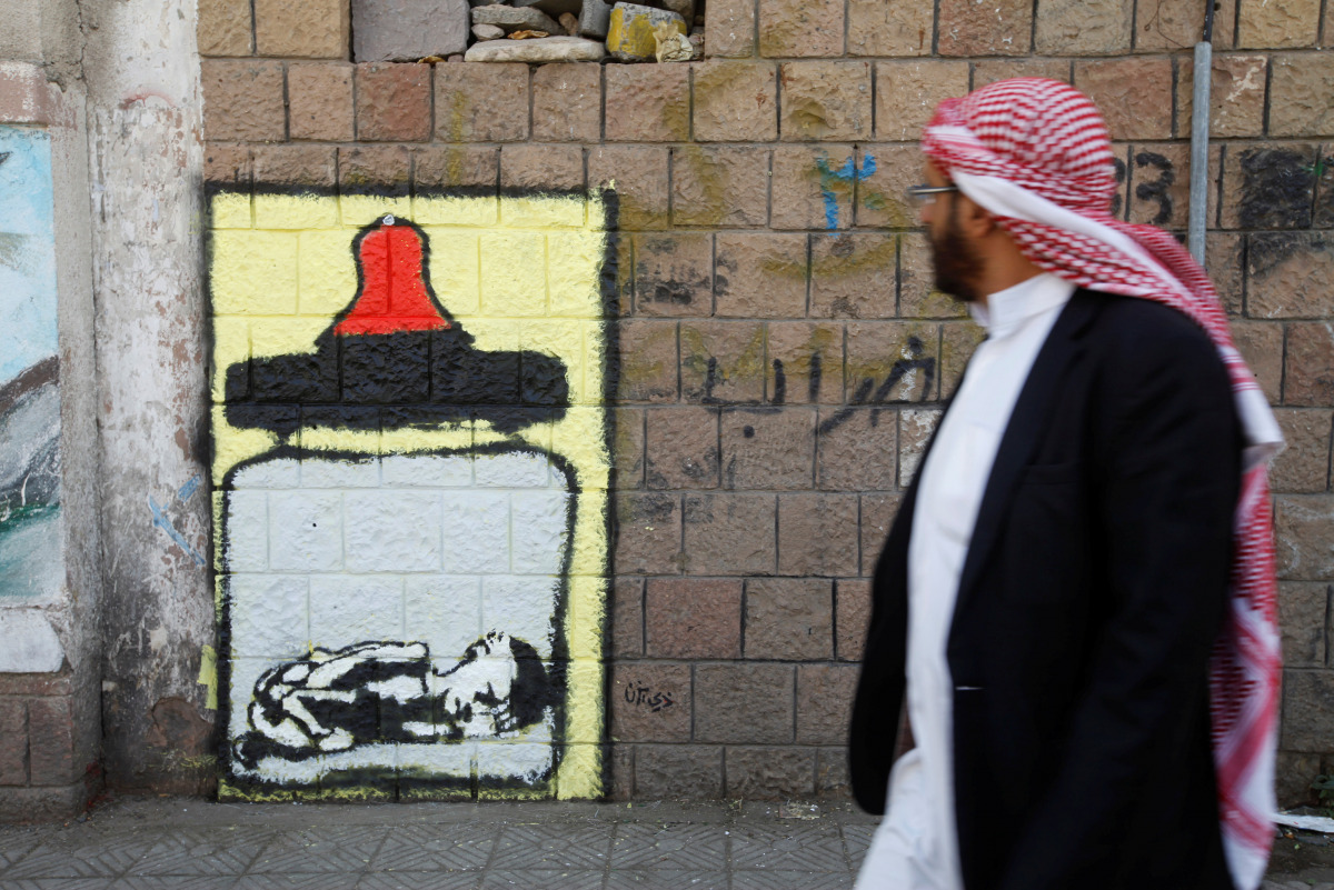 A man walks pass a graffiti by artist Thi Yazen AL-Alawy depicting a bottle of milk with a malnourished child inside along a street in Sanaa, Yemen, October 20, 2016. The graffiti is part of a campaign by several artists titled 