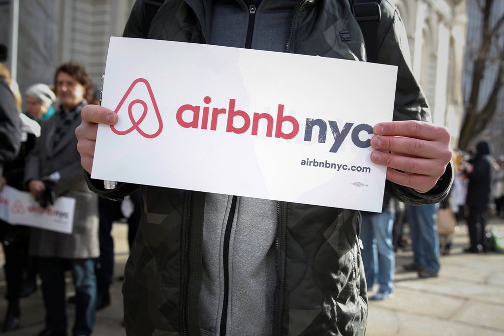 Supporters of Airbnb stand during a rally before a hearing called 