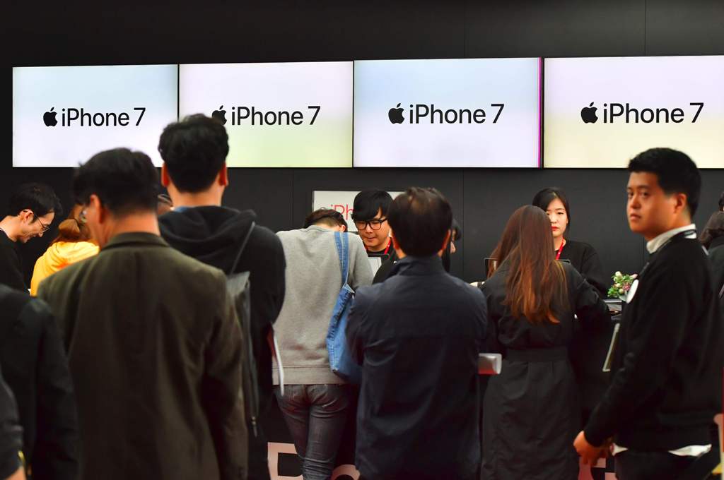 People wait in line to buy new iPhone models at a telecom shop in Seoul on October 21, 2016. Apple released for sale its new iPhone 7 and 7 Plus in South Korea on October 21. / AFP / JUNG YEON-JE

