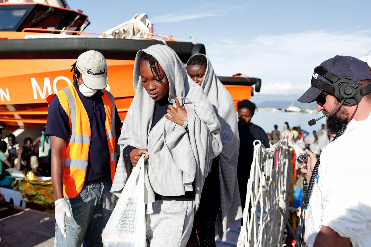 This handout picture taken and released by the Italian Red Cross on October 22, 2016 shows migrants landing in Vibo Marina, after a rescue operation in the Mediterranean Sea. Nine people drowned, ten were missing and nearly 1000 migrants were rescued off 