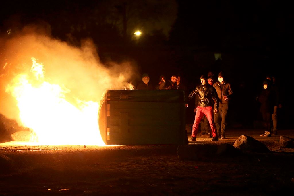 Flames are seen near protesters on the eve of the evacuation and transfer of migrants to reception centers in France, and the dismantlement of the camp called the 
