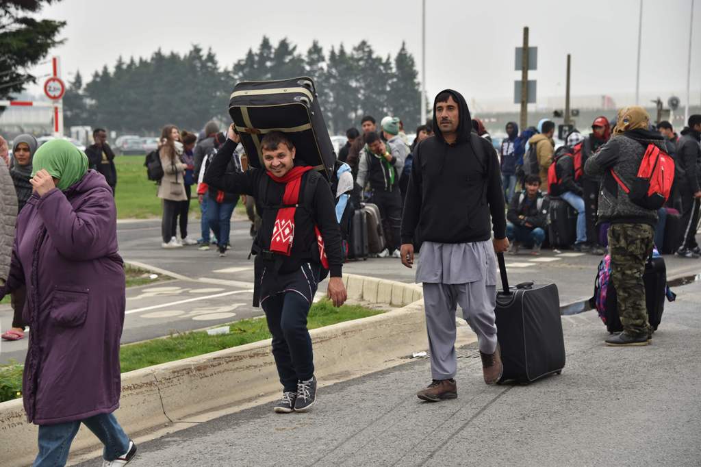 Migrants with their luggage queue to leave the 