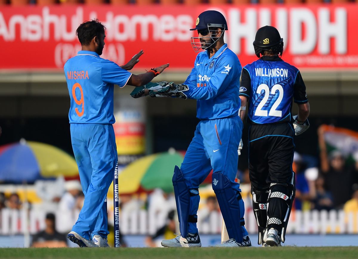 Indian bowler Amit Mishra (L) celebrates with team captain Mahendra Singh Dhoni after dismissing New Zealand batsman and captain Kane Williamson during the fourth one day international (ODI) cricket match between India and New Zealand at The Jharkhand Sta