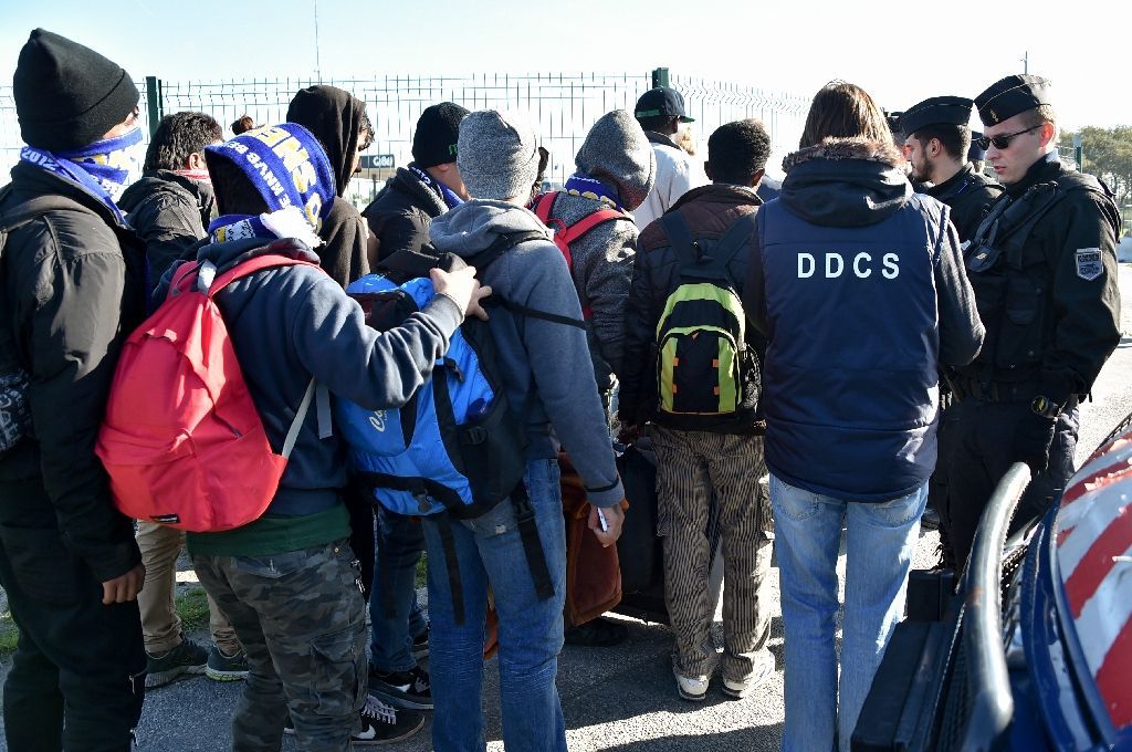 French police officers and charity workers escort young migrants to board a bus leaving for a reception centre, in Calais, on October 28, 2016 (AFP Photo/Philippe Huguen)