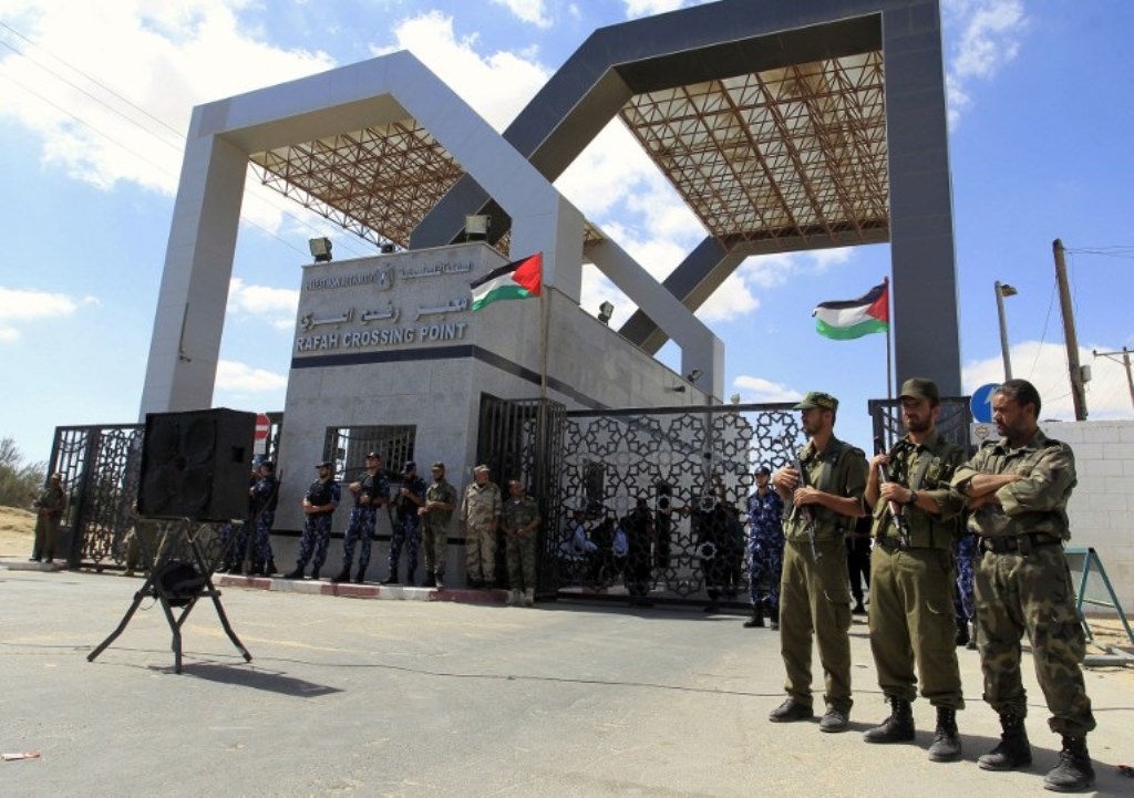 A picture taken on September 16, 2013 shows members of Hamas’ security forces standing guard in front of the Rafah border crossing with Egypt in the southern Gaza Strip as demonstrators gather demanding it to be open permanently and without restrictions o