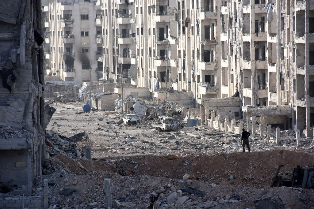 A member of the Syrian pro-government forces stands amid heavily damaged buildings in Aleppo's 1070 district on November 8, 2016, after troops seized it from rebel fighters.  AFP / GEORGES OURFALIAN
