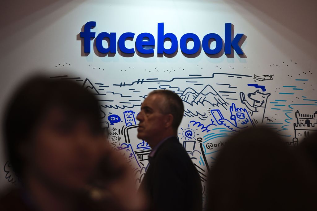 People pass by the stand of Facebook during the Web Summit at Parque das Nacoes, in Lisbon on November 9, 2016. AFP / PATRICIA DE MELO MOREIRA
