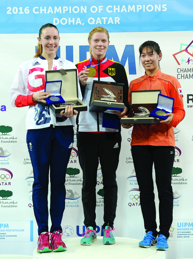2016 Champion of Champions, German pentathlete Annika Schleu (centre), silver medallist  Samantha Murray of Great Britain (left) and bronze medallist Sehee Kim of South Korea pose for a picture on the podium following the awards ceremony at Al Shaqab Aren