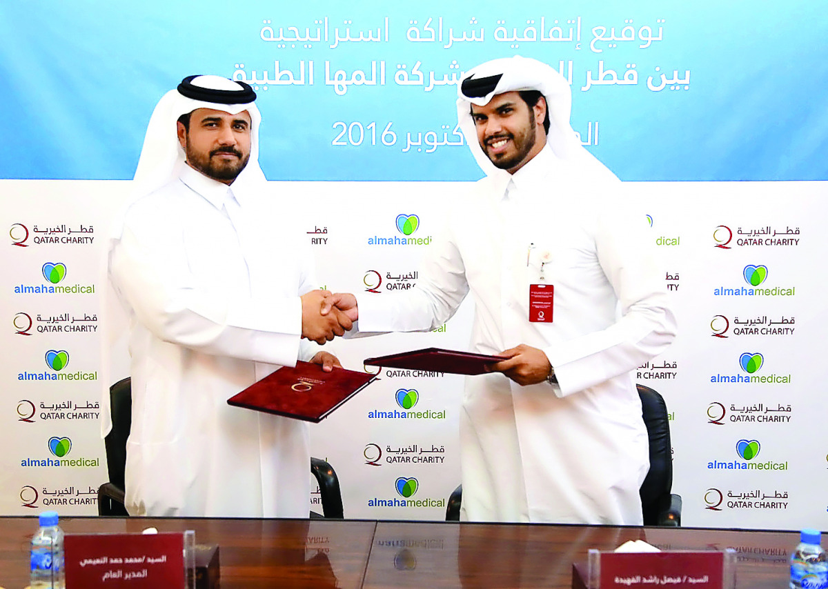 Faisal Rashid Alfahidh (right), Executive Director for Operations Management at Qatar Charity, and Dr Mohammed bin Hamad Al Naimi, General Director at Almaha Medical, exchanging documents after signing the agreement.