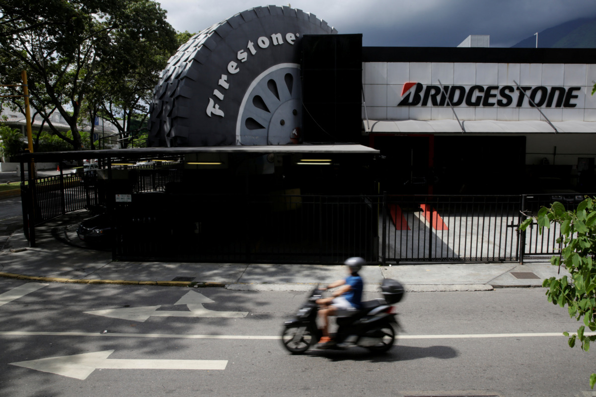 A motorcyclist ride past a Bridgestone Firestone tires store in Caracas, Venezuela November 5, 2016. REUTERS/Marco Bello