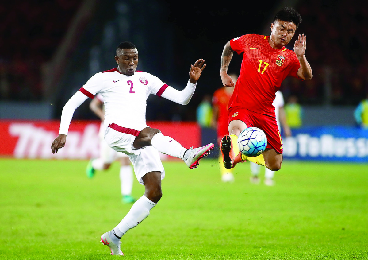 Cao Yunding of China (right) competes for the ball with Mohamed Musa of Qatar during their 2018 FIFA World Cup qualifying match in Kunming, in China's Yunnan province, yesterday. The match ended goalless. 