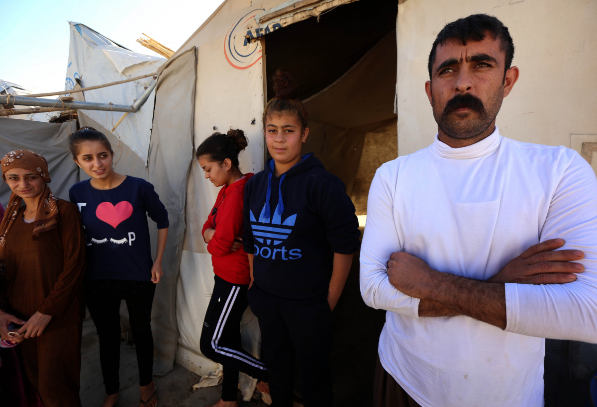 Ali Mahmud (R), a displaced Iraqi man from the Yazidi community who fled violence between Islamic State (IS) group jihadists and Peshmerga fighters in the northern town of Bashiqa, stands with family members outside a tent at a camp for internally displac